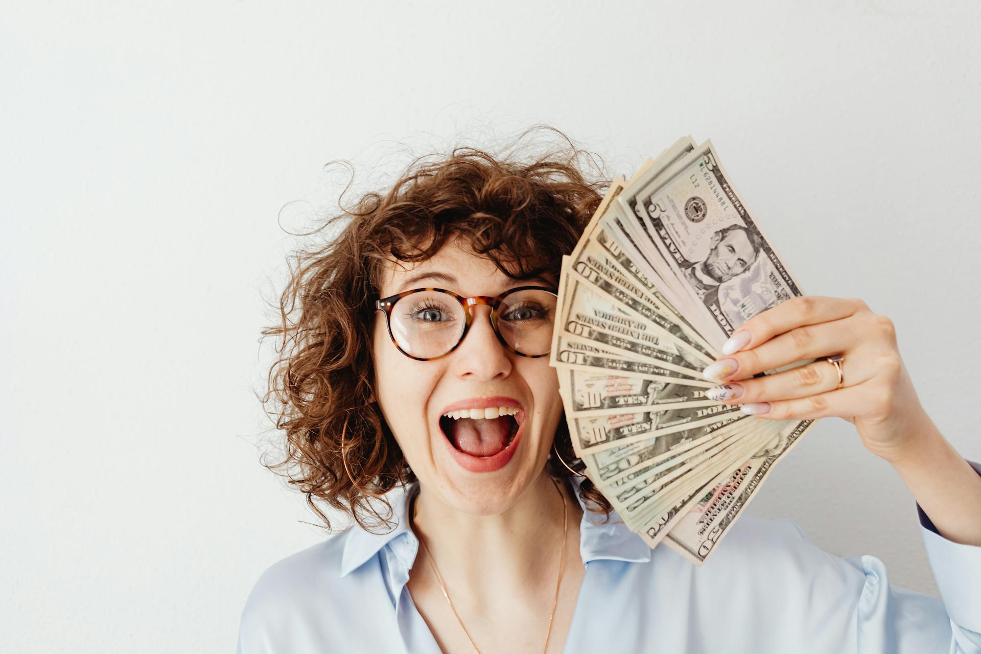 A happy woman holding banknotes | Source: Pexels