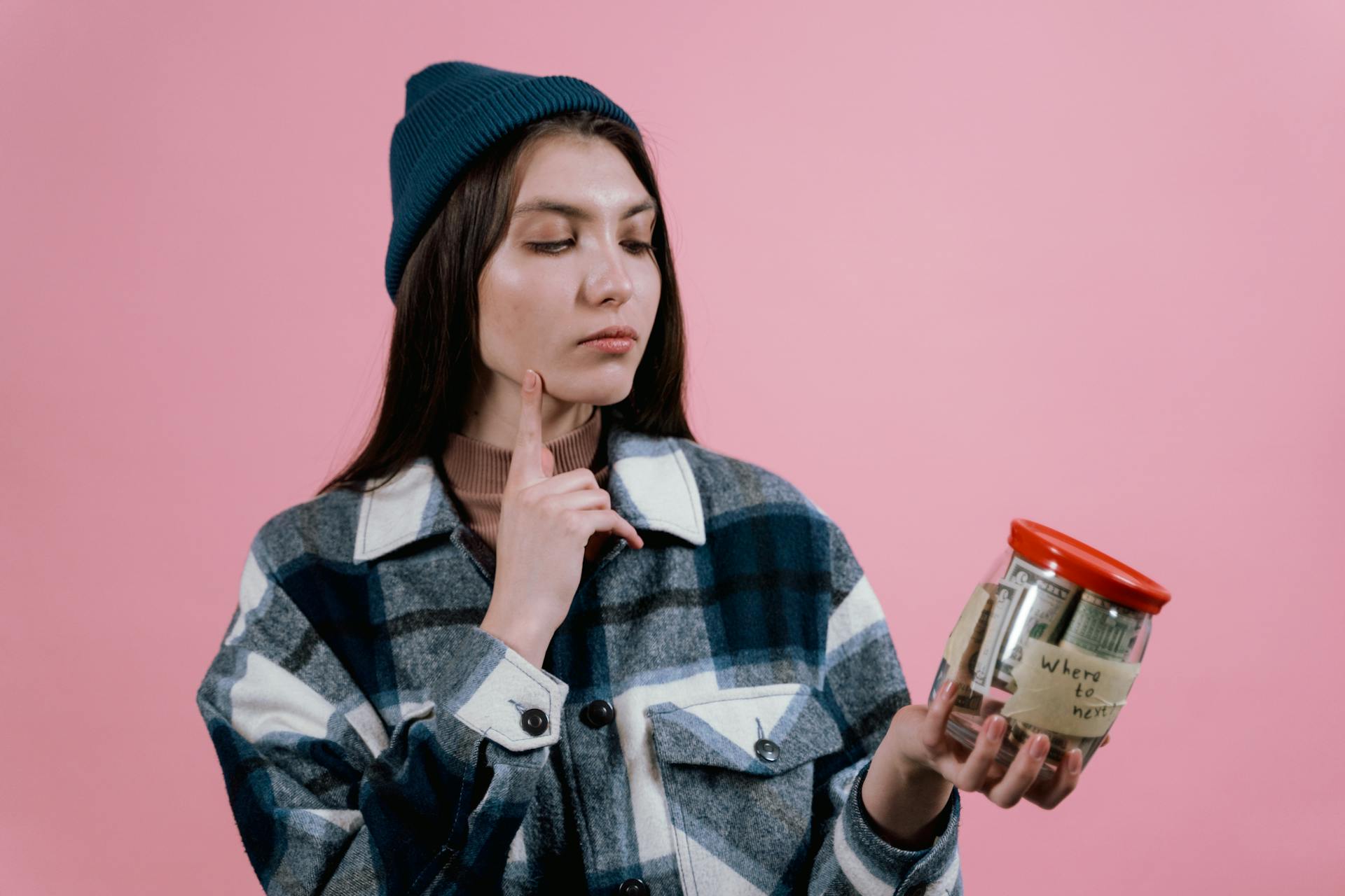 A woman holding a glass jar containing money | Source: Pexels