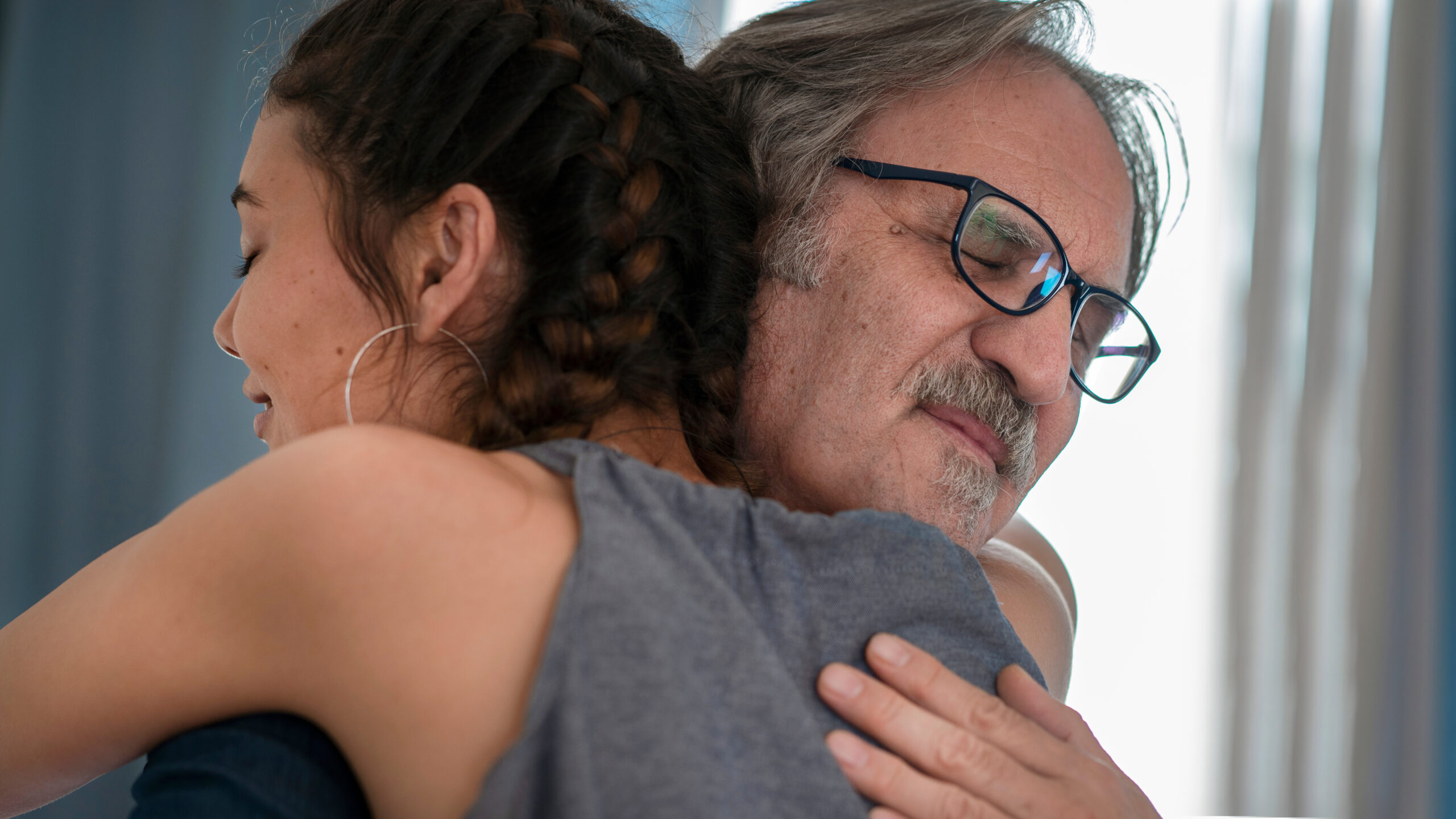 An older man hugs a younger woman | Source: Shutterstock