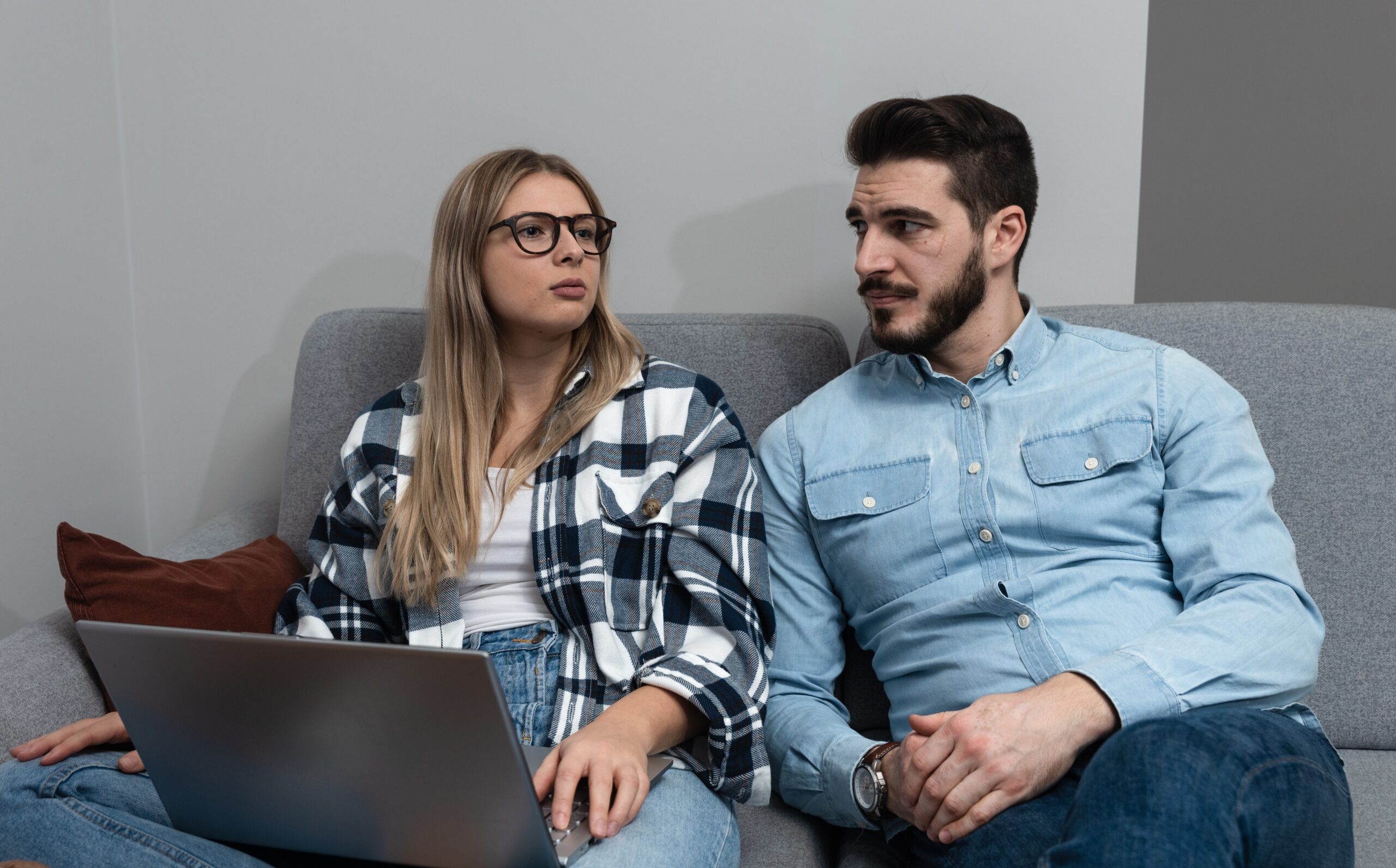 A couple seated together discussing something while a laptop sits on the woman's lap | Source: Shutterstock