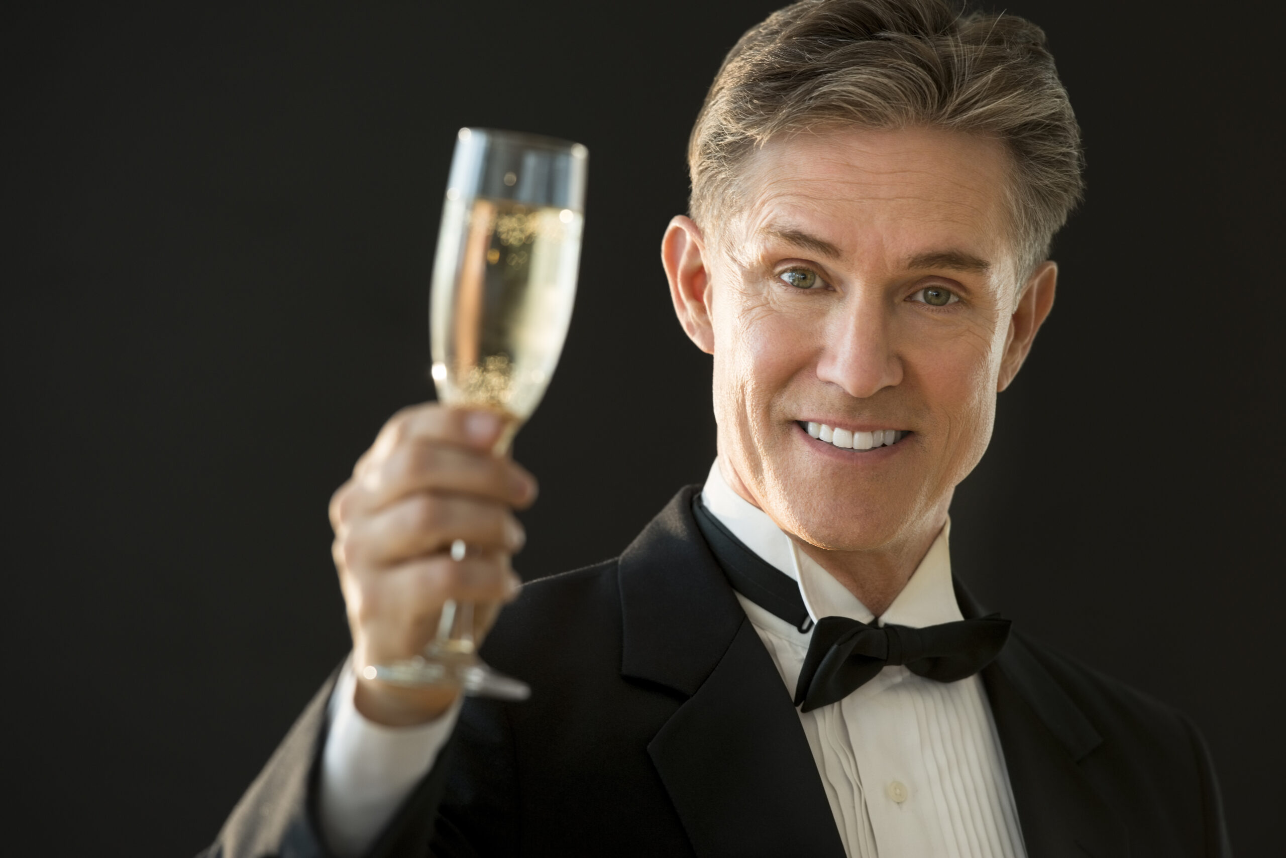 A happy older man raises a toast at an event | Source: Shutterstock