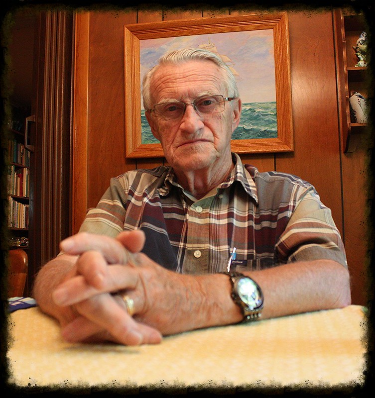 A resolute looking older man sitting with his hands clasped together | Source: Flickr