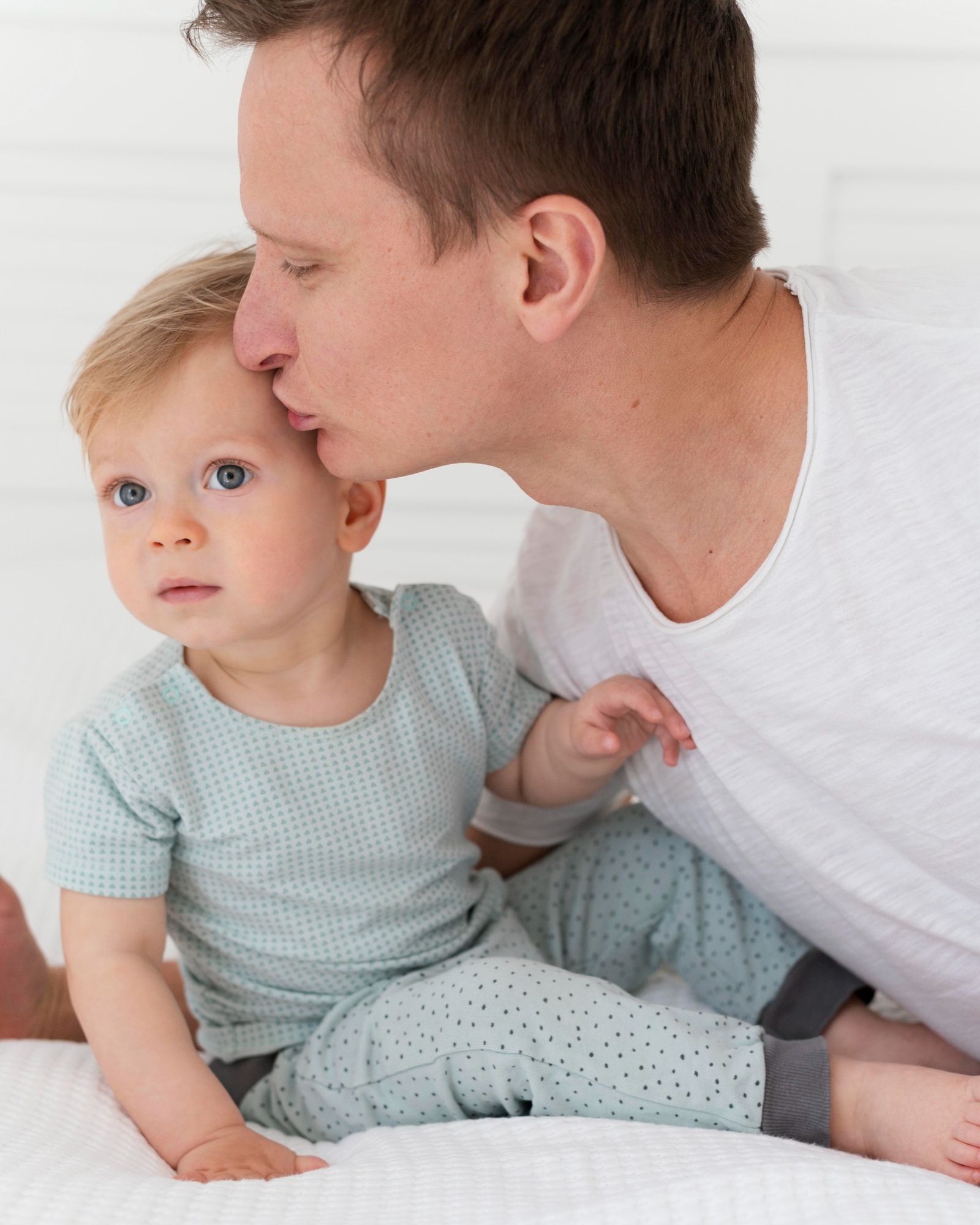 A young man kissing a baby's head | Source: Freepik