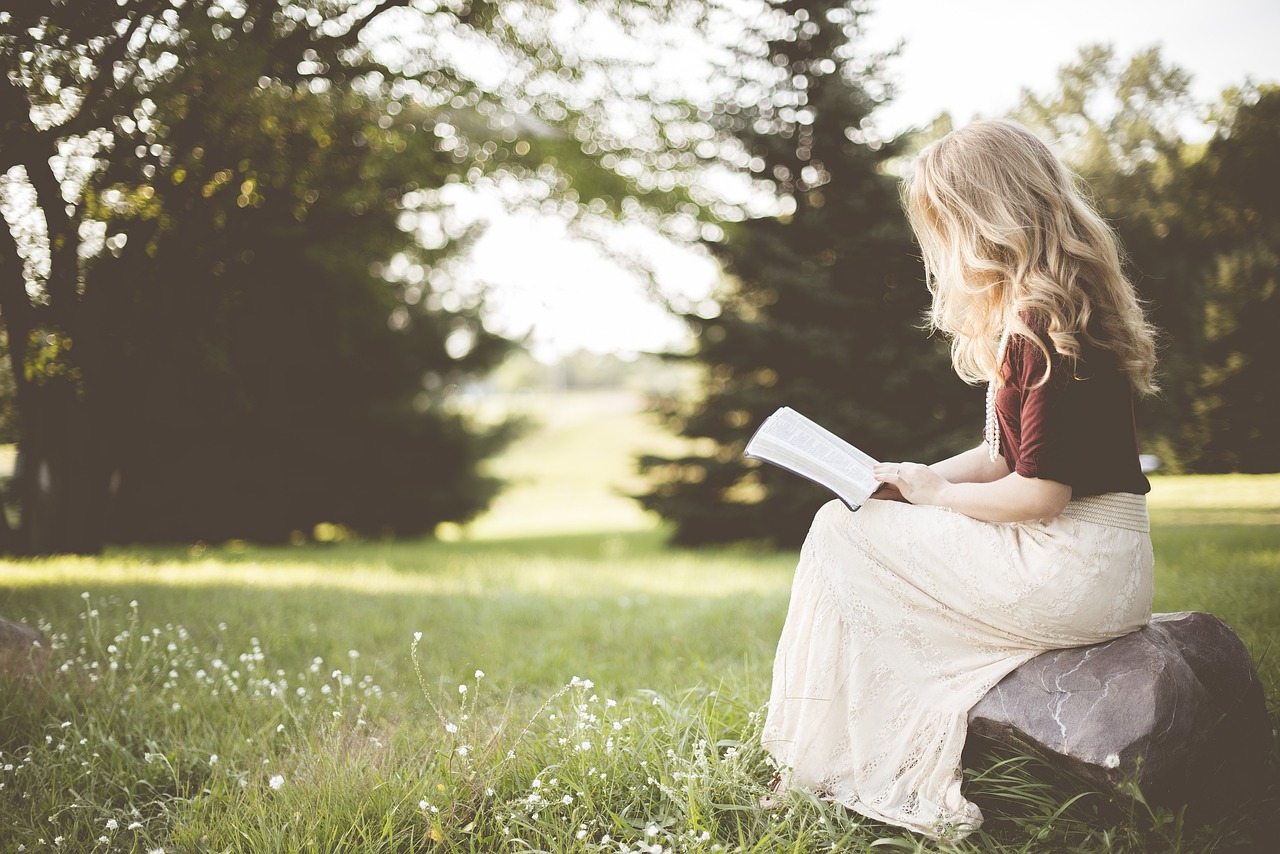 A woman reading a book outside | Source: Pixabay