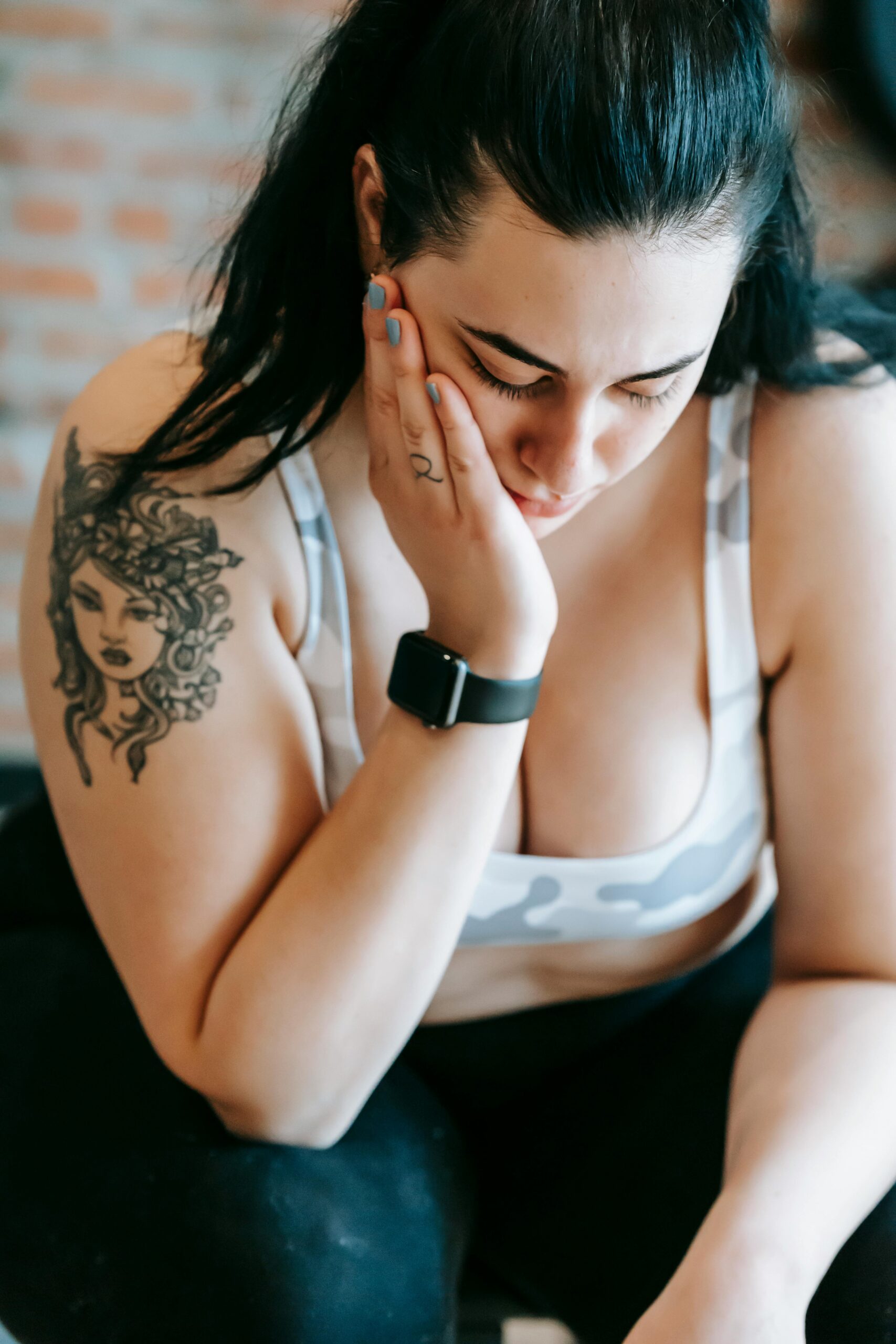 A frustrated woman holding her cheek while looking down | Source: Pexels