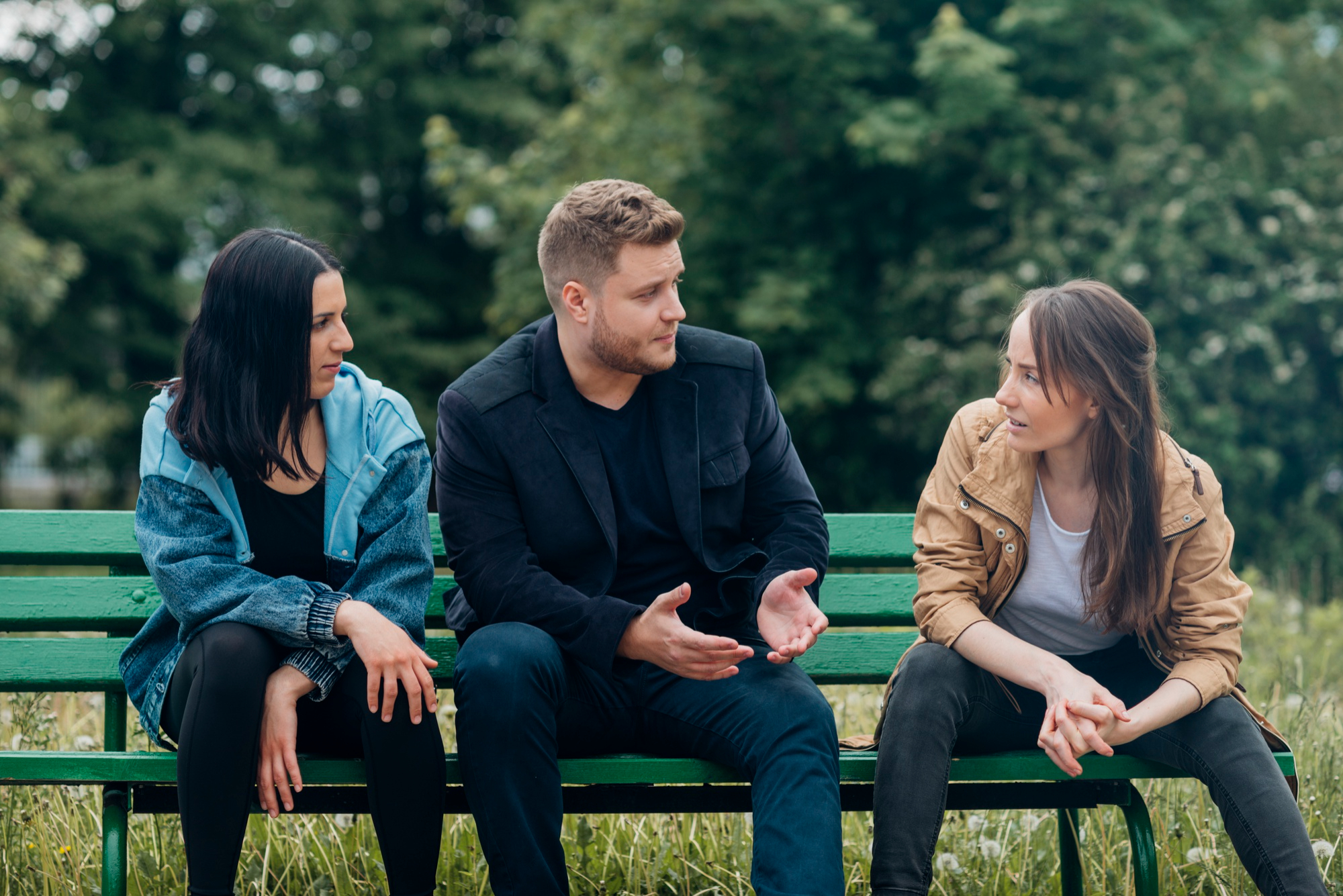 A couple talking to another woman while seated on a bench | Source: Freepik