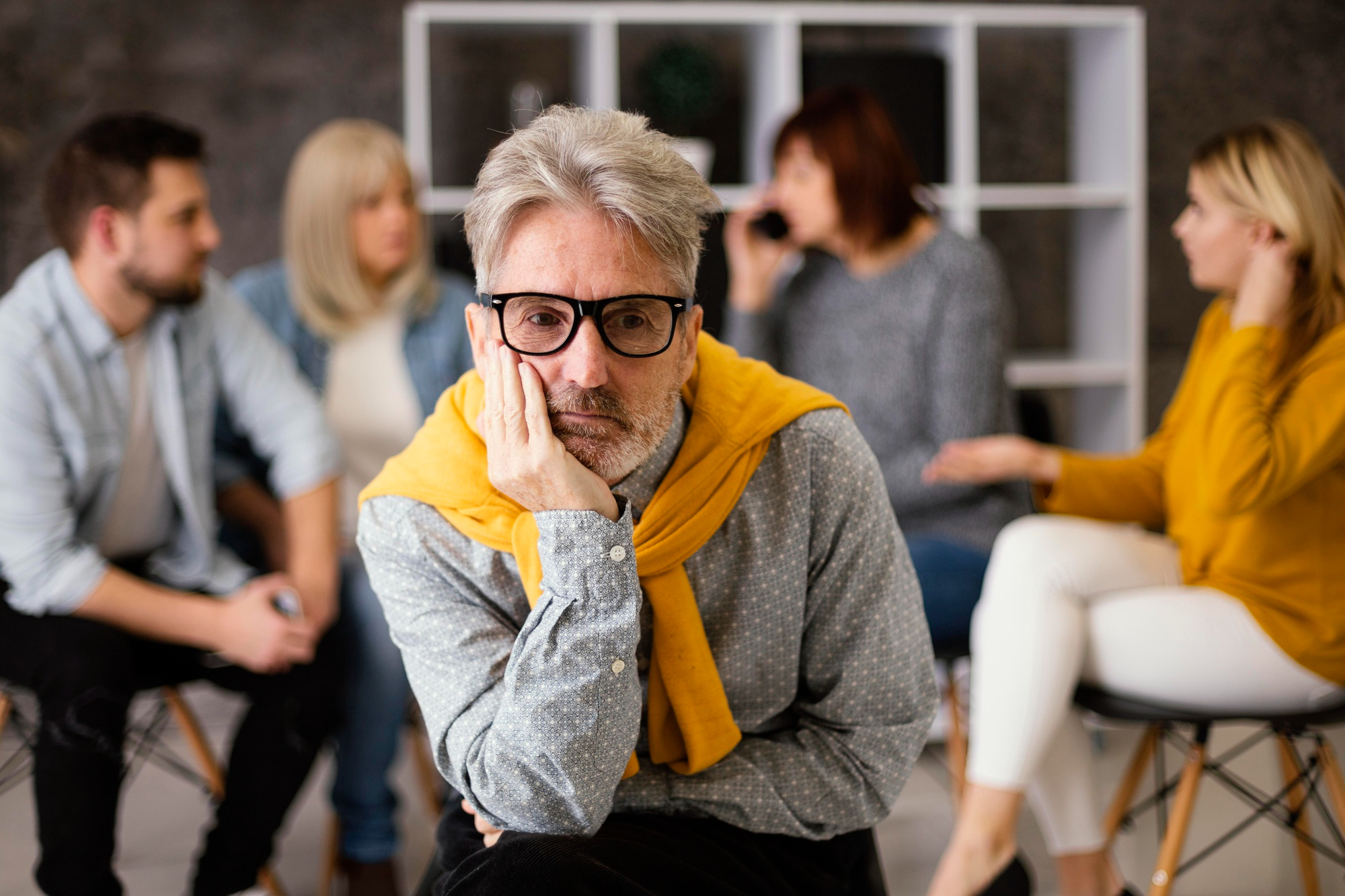 An embarrassed man looking dejected with people behind him | Source: Freepik