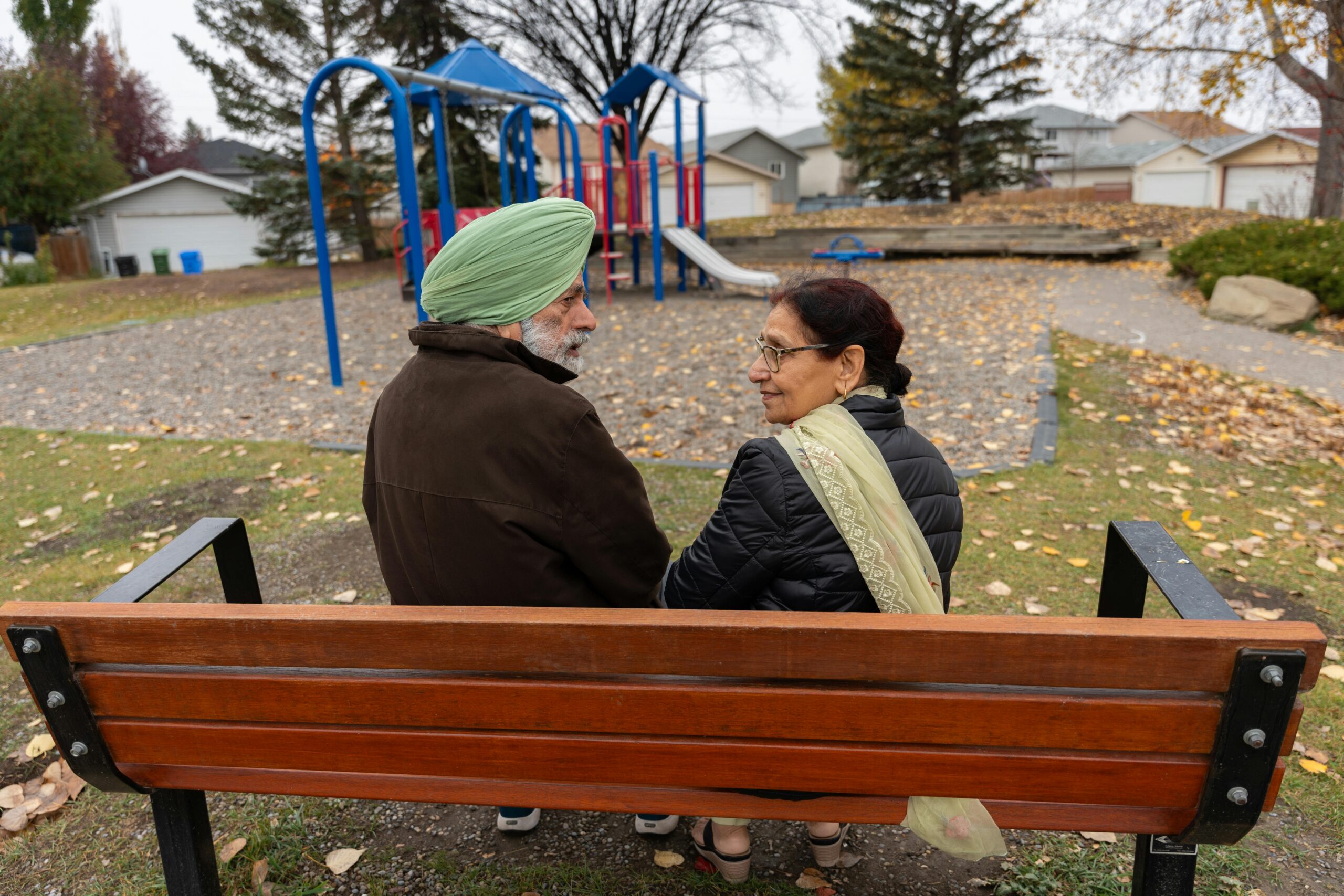 A middle-aged couple looking behind their backs while seated on a bench | Source: Pexels