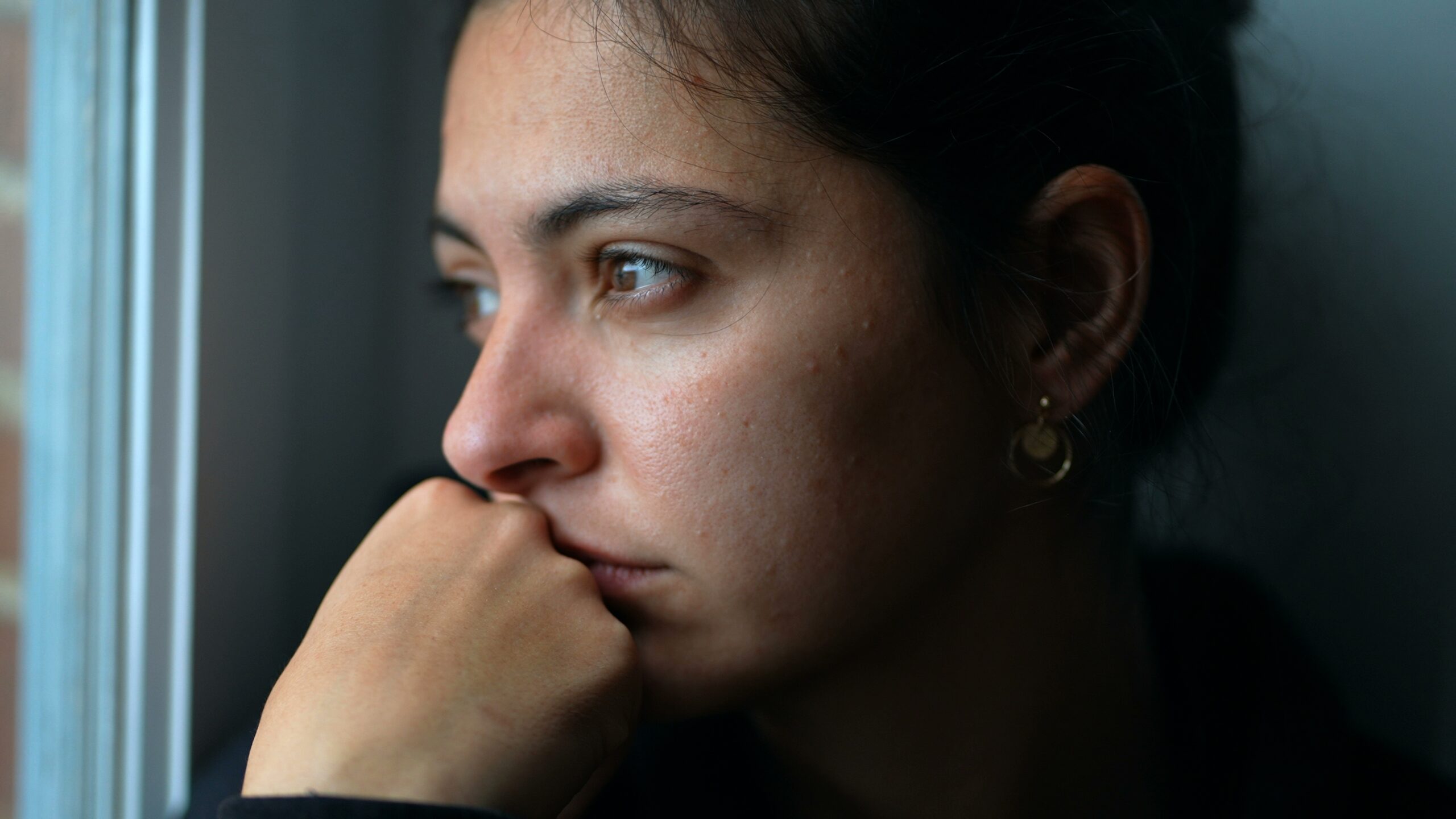 A young woman lost in thoughts looking through the window | Source: Shutterstock