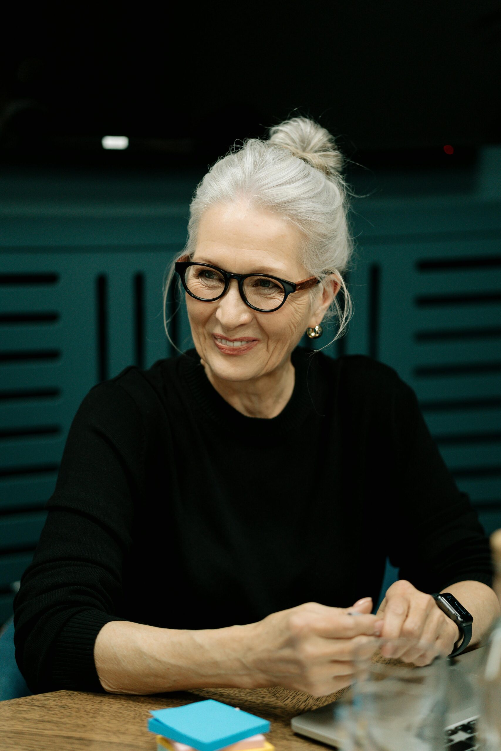 An older woman smiling while seated at a table | Source: Pexels