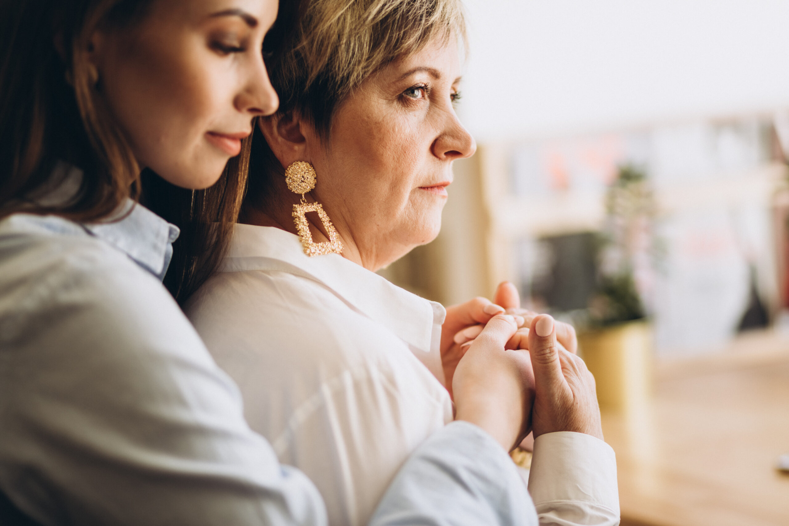 A young woman hugs an elder woman | Source: Shutterstock