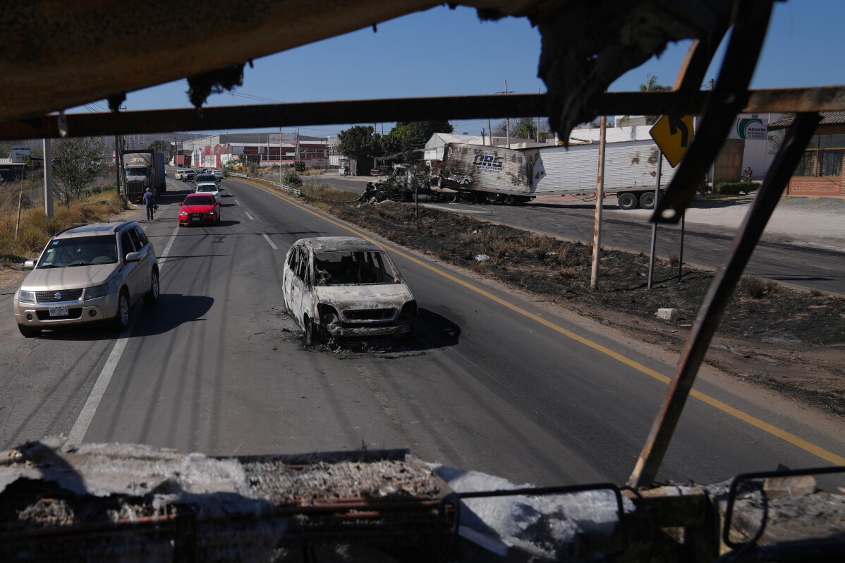 Vehicles pass a burned car a day after the Mexican army killed the leader of the Jalisco New Generation Cartel, Nemesio Oseguera Cervantes