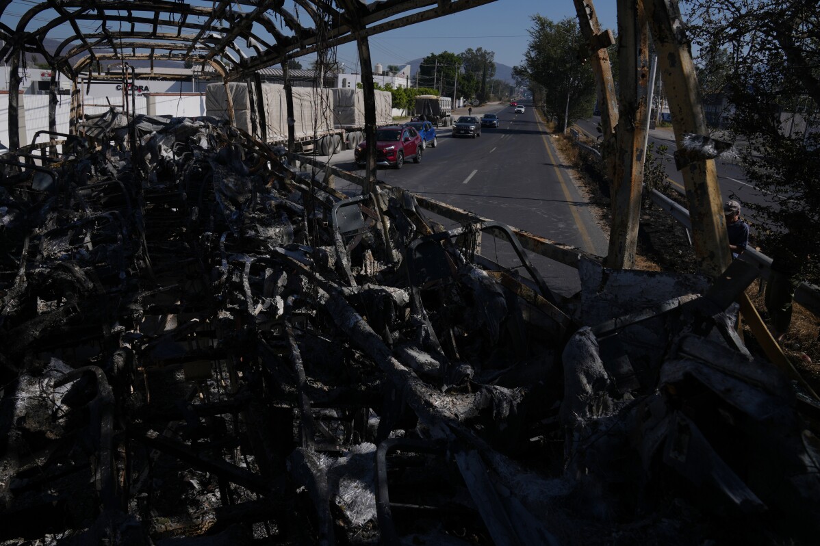 Vehicles drive past a charred bus the day after the Mexican army killed Jalisco New Generation Cartel leader Nemesio Oseguera Cervantes