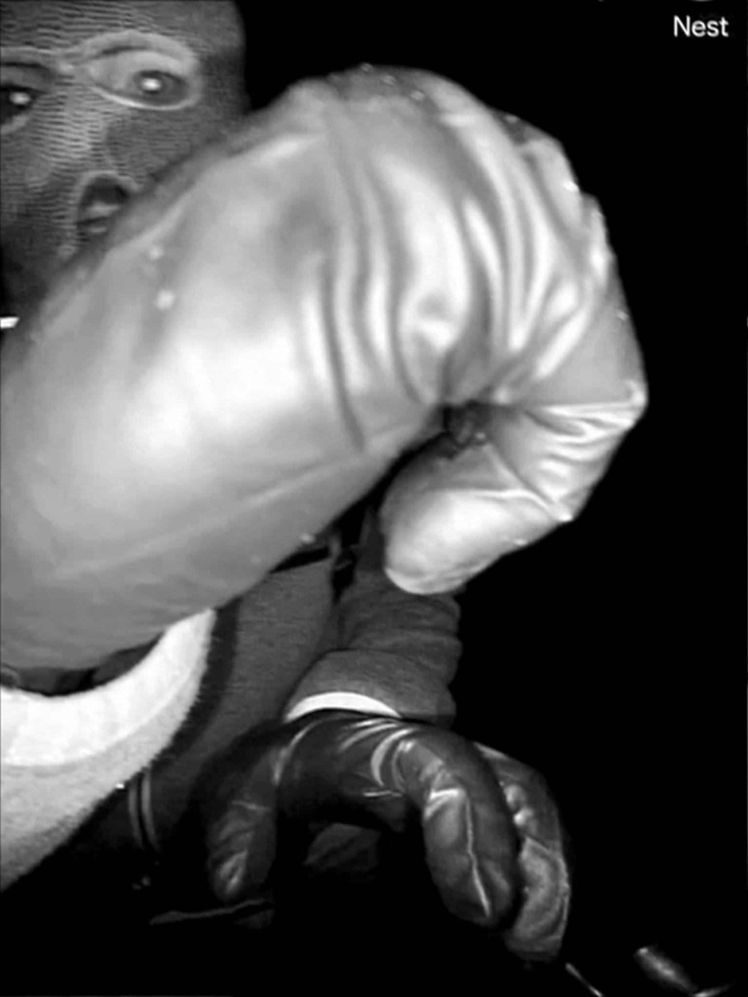 Surveillance image of a suspect wearing a balaclava and gloves.
