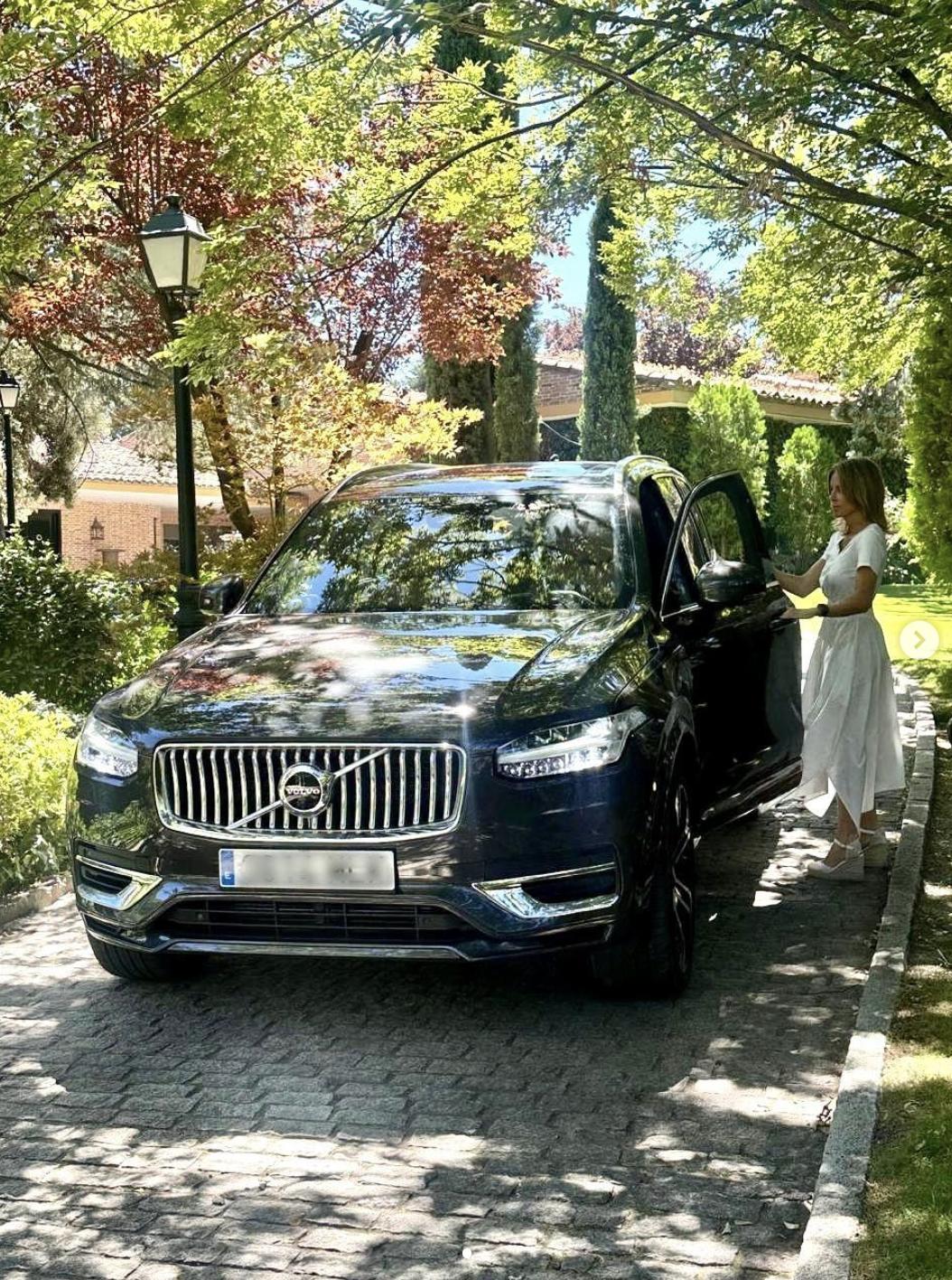 A cobblestone driveway lined with mature trees, manicured greenery, and lantern-style lights leads toward the family's residence in Spain.