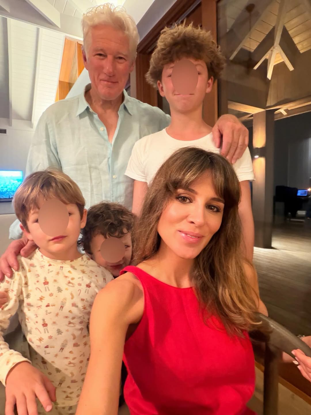 Richard Gere and Alejandra Silva pose with their children inside the family's Spain home, where exposed beams, wood accents, and warm lighting create a cozy setting for family gatherings.