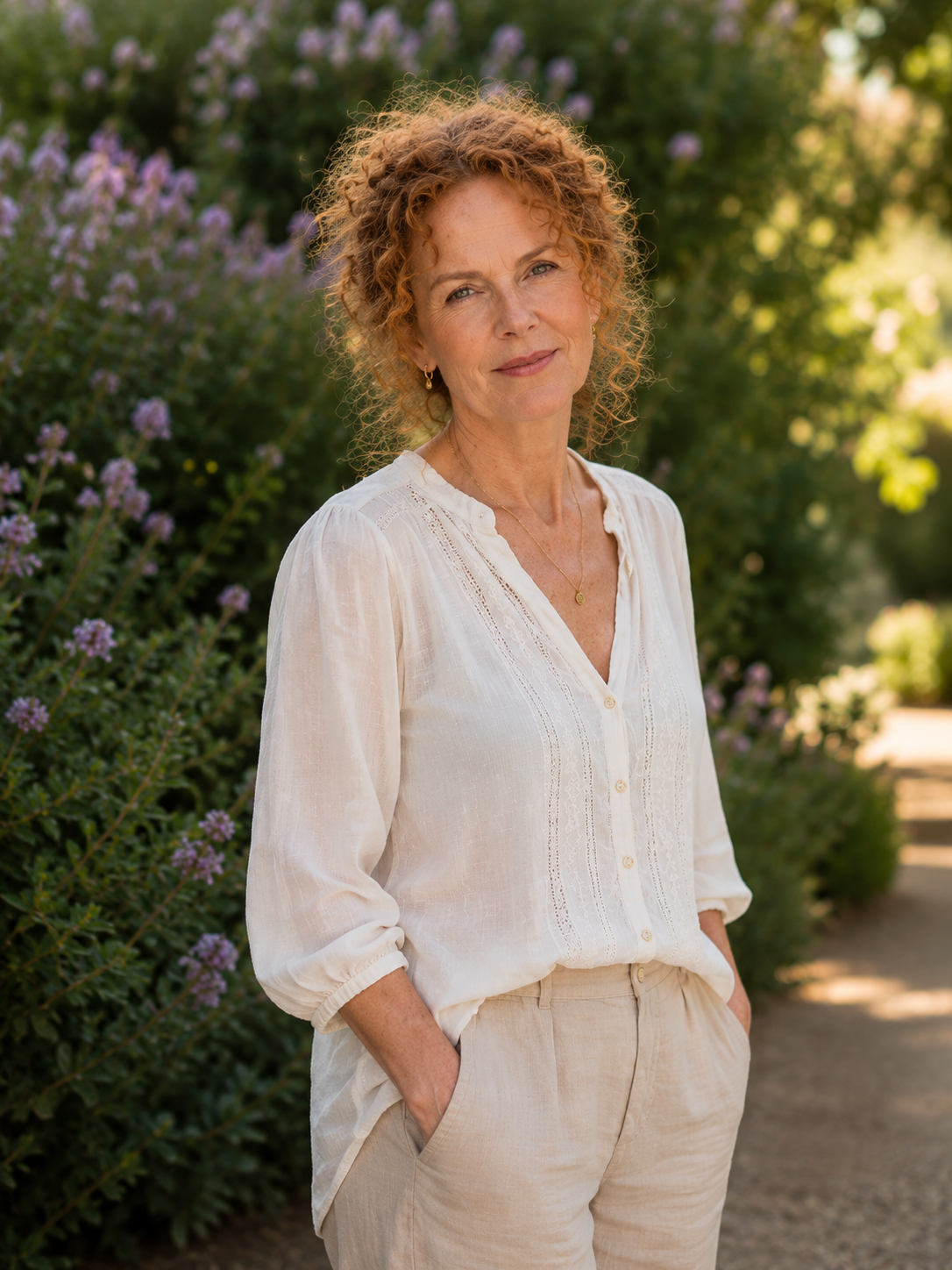 In this medium close-up, the coppery, tightly coiled curls she first became known for frame a beautifully weathered face. The authentic pattern of freckles and the interconnected network of crow's feet and laugh lines create a rich tapestry of realism, rejecting any glassy perfection to showcase a soft, mobile complexion.