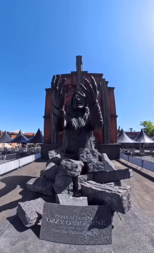 With his arms raised and face turned upward, Ozzy Osbourne's likeness appears to emerge from fractured stone in Philippe Pasqua's six-meter-tall tribute at Hellfest.