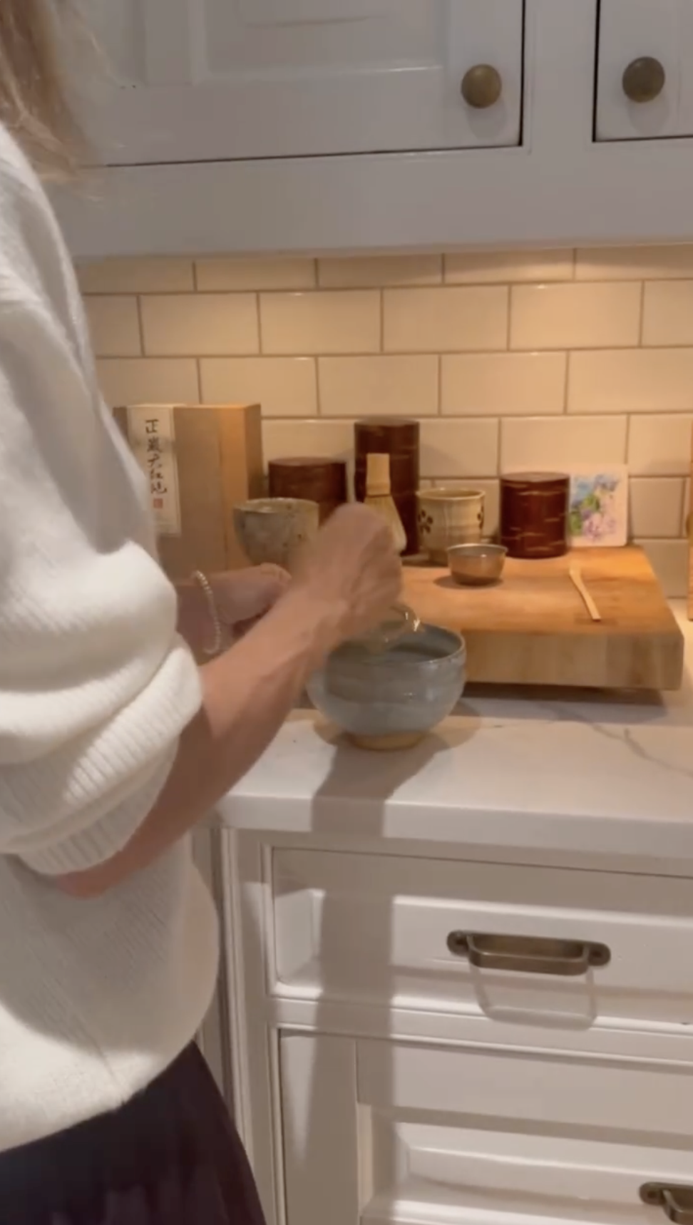Alejandra Silva prepares a drink in the kitchen, where ceramic bowls, wooden containers, and tea accessories add a personal touch to the family-focused space.
