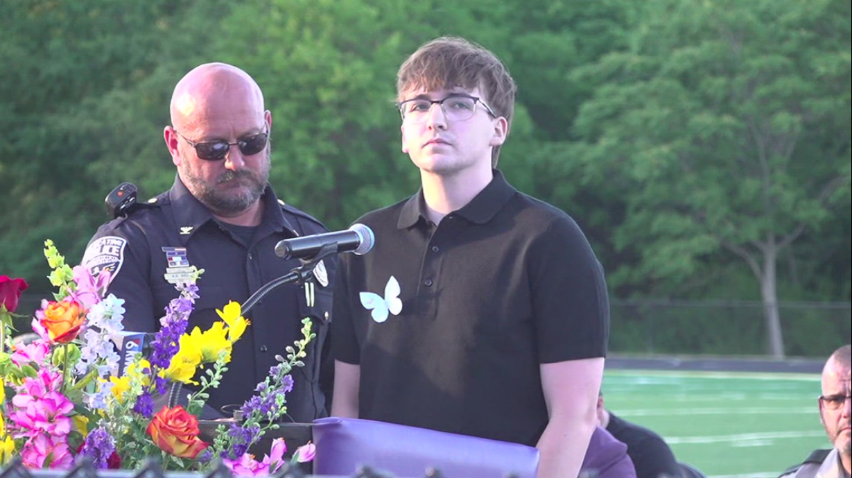 The Police Chief stands beside Jonathan McFarland who speaks during a community vigil for his family members killed in the Muscatine, Iowa, shooting spree. The sole surviving sibling addressed mourners as the community gathered to honor the victims.