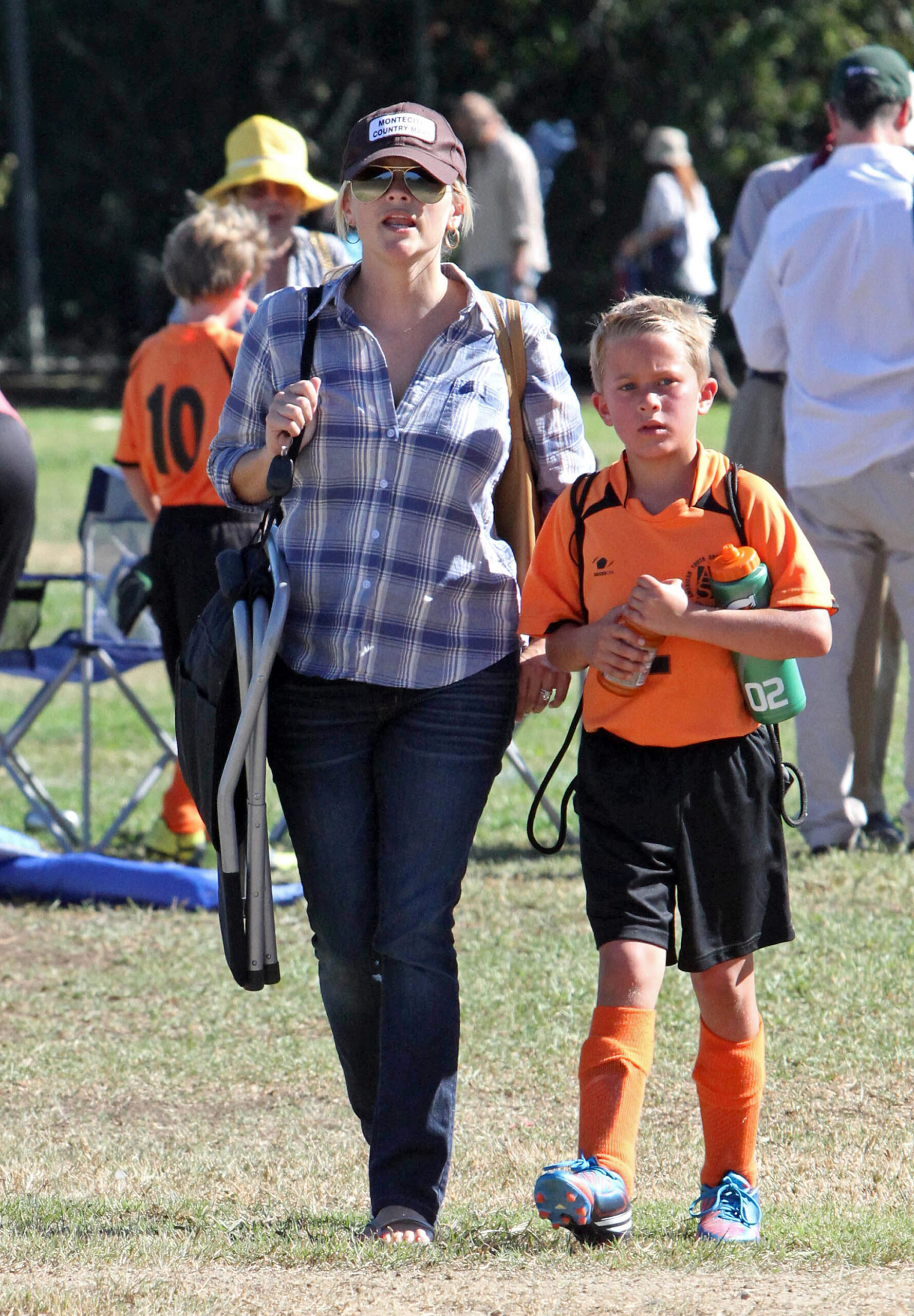 Reese Witherspoon walks with Deacon Phillippe in Los Angeles, dressed casually in a plaid shirt and jeans as he wears a bright orange soccer uniform.