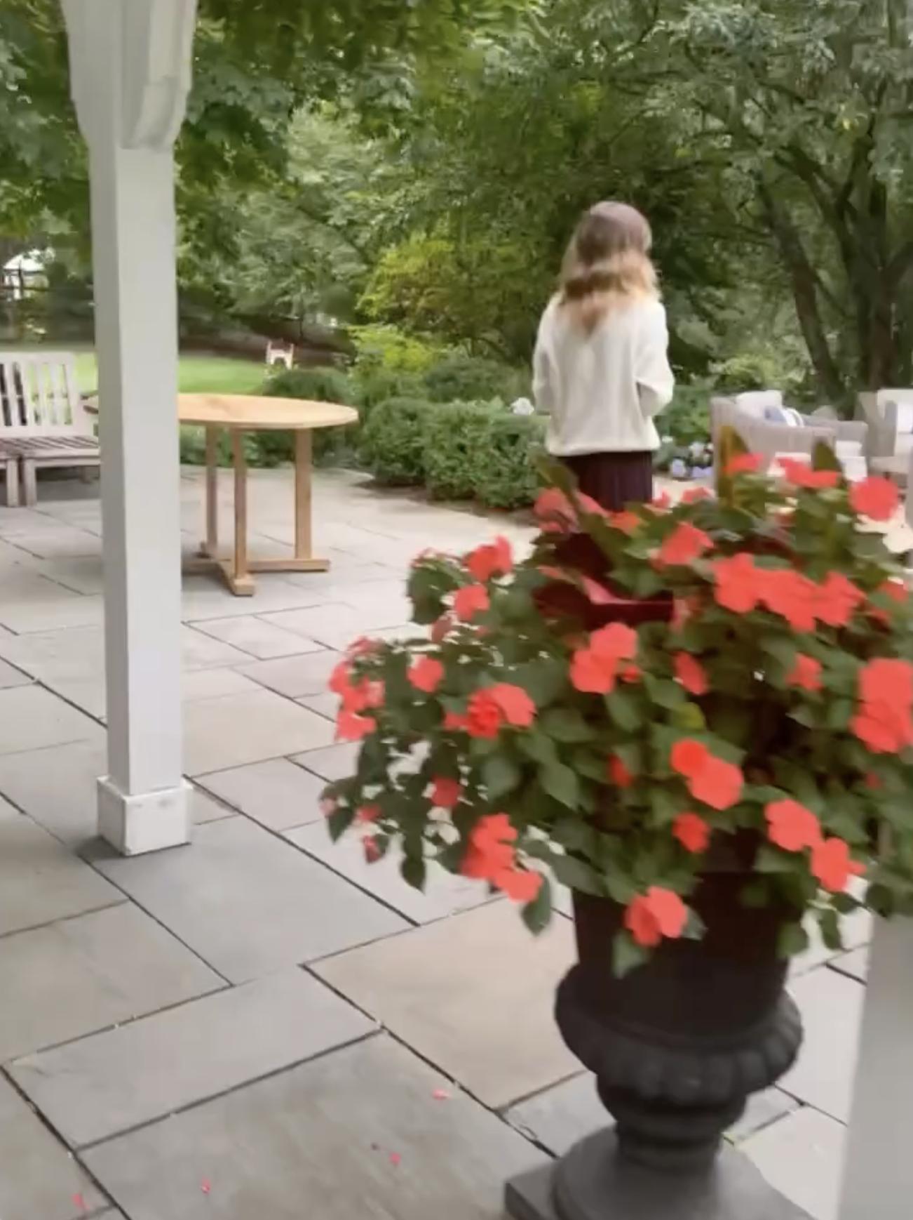 Silva shared a view of a covered outdoor seating area featuring wooden tables, benches, and potted flowers overlooking the gardens.