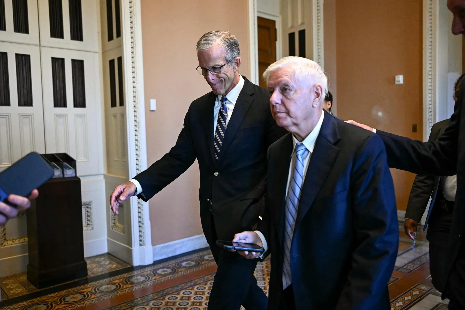 Lindsey Graham walks through the U.S. Capitol with Senate Majority Leader John Thune during the final weeks of his Senate service. The medical examiner has emphasized that the reported cause of death is preliminary and could be updated after routine toxicological and microscopic testing is complete.