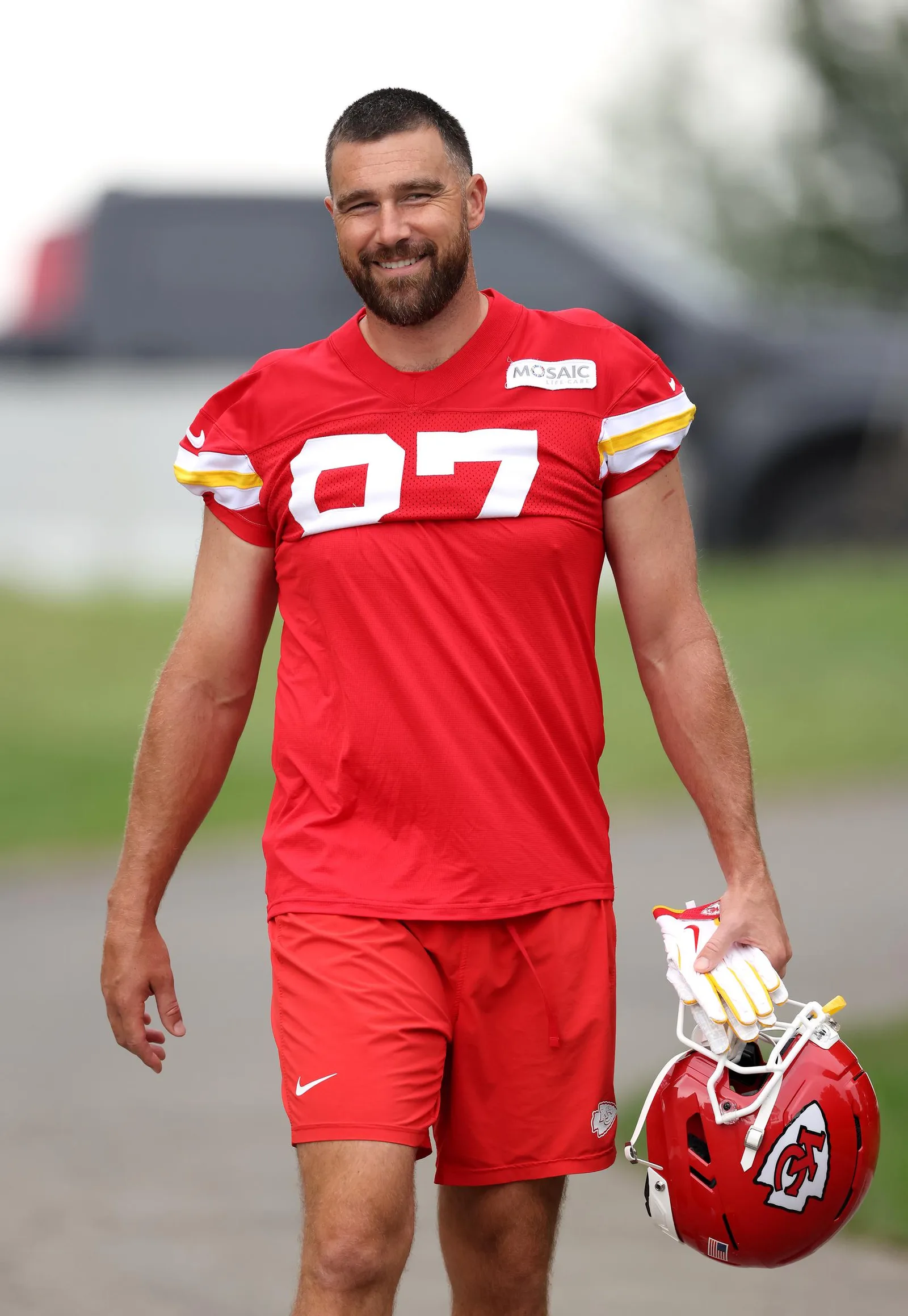 Travis Kelce arrives at the Kansas City Chiefs' training camp in St. Joseph, Missouri, carrying his helmet as he begins preparations for his 14th NFL season—just weeks after marrying Taylor Swift.