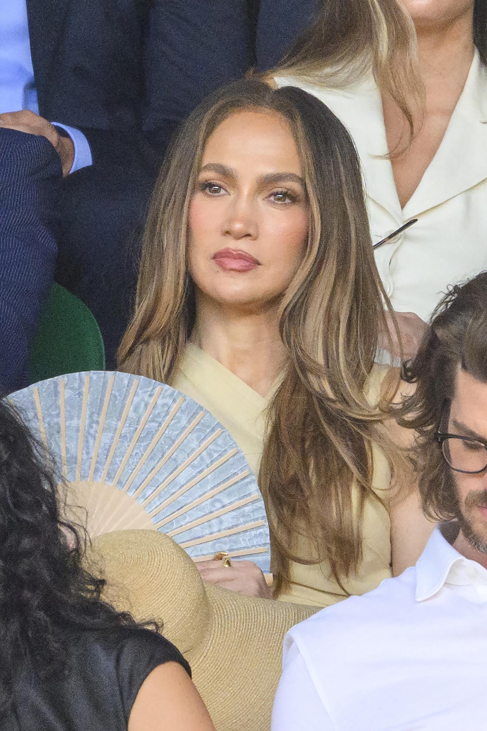 A decorative folding fan added another refined detail to the neutral look while offering relief from the summer heat. The accessory complemented her ensemble without generating the same heated response as the hat.