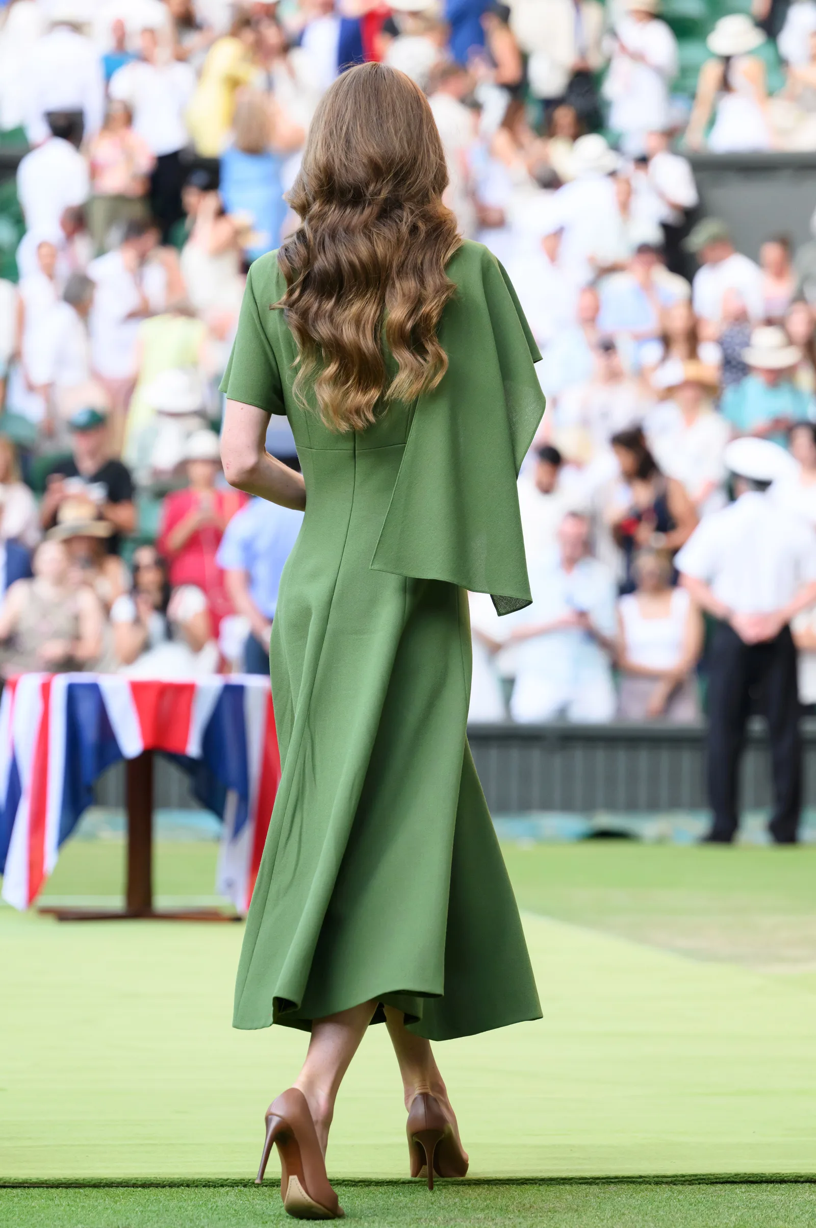 This rear view highlights the flowing silhouette of Catherine's custom Emilia Wickstead dress as she crossed Centre Court. The elegant design reflected the understated style she chose for the final day of the Championships.
