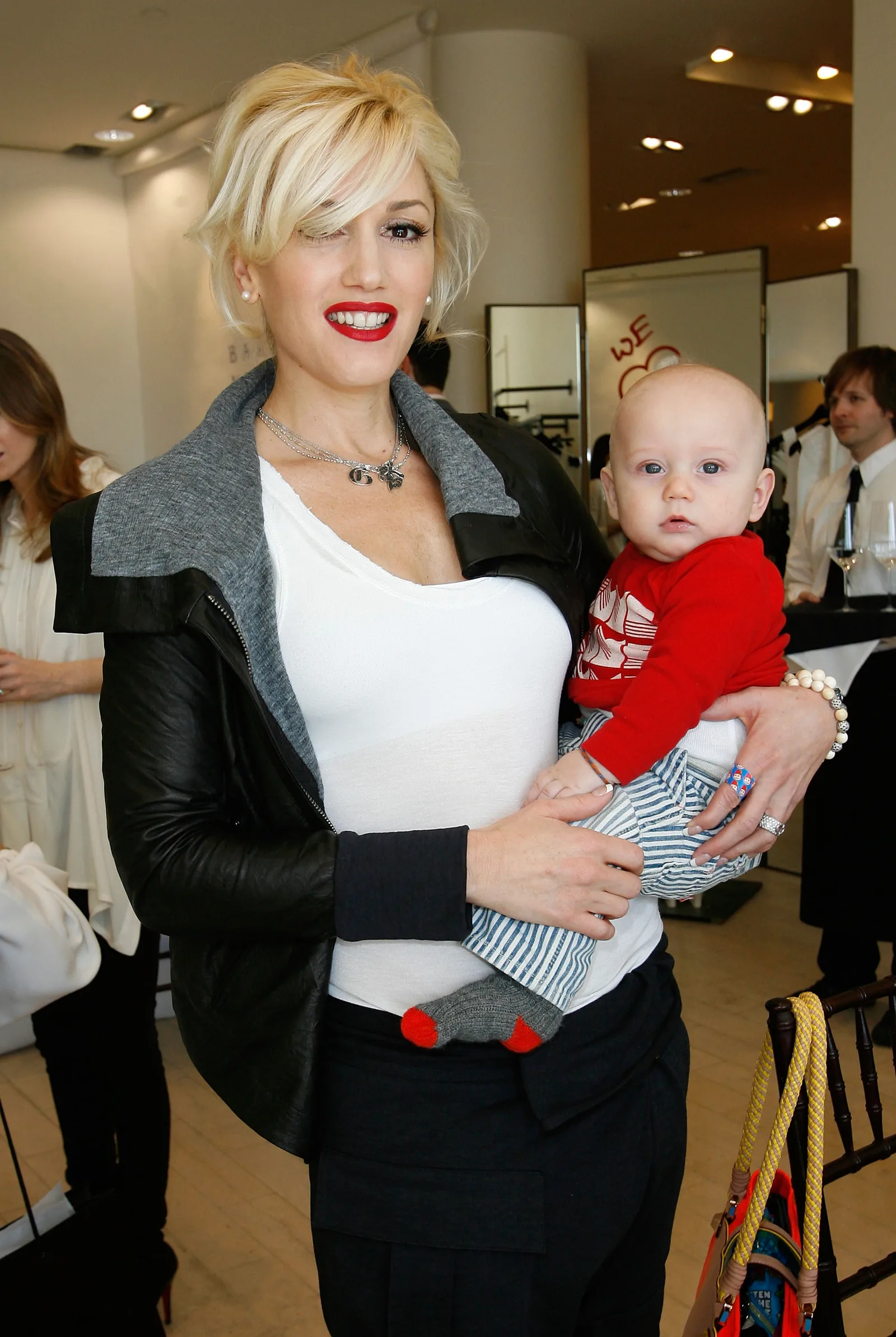 Gwen Stefani smiled as she held her baby son Zuma Rossdale, who looked adorable in a red long-sleeve top and striped pants with a baby bald head. At this event, they attended the celebration for Andrea Lieberman hosted by Barneys New York and Jennifer Lopez on February 18, 2009, in Beverly Hills, California.
